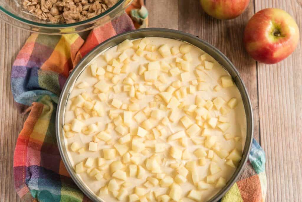 cheesecake with diced apples on top before baking