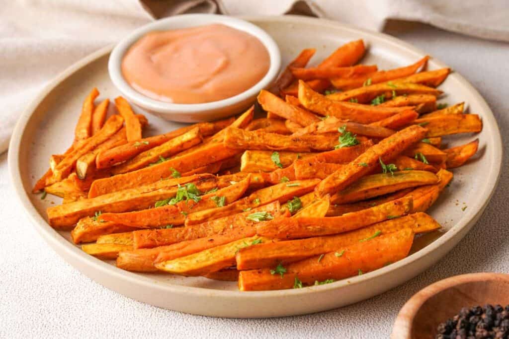 sweet potato fries and dipping sauce on tan plate