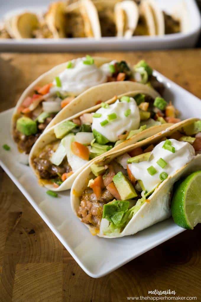 Three baked soft tacos on a small white platter