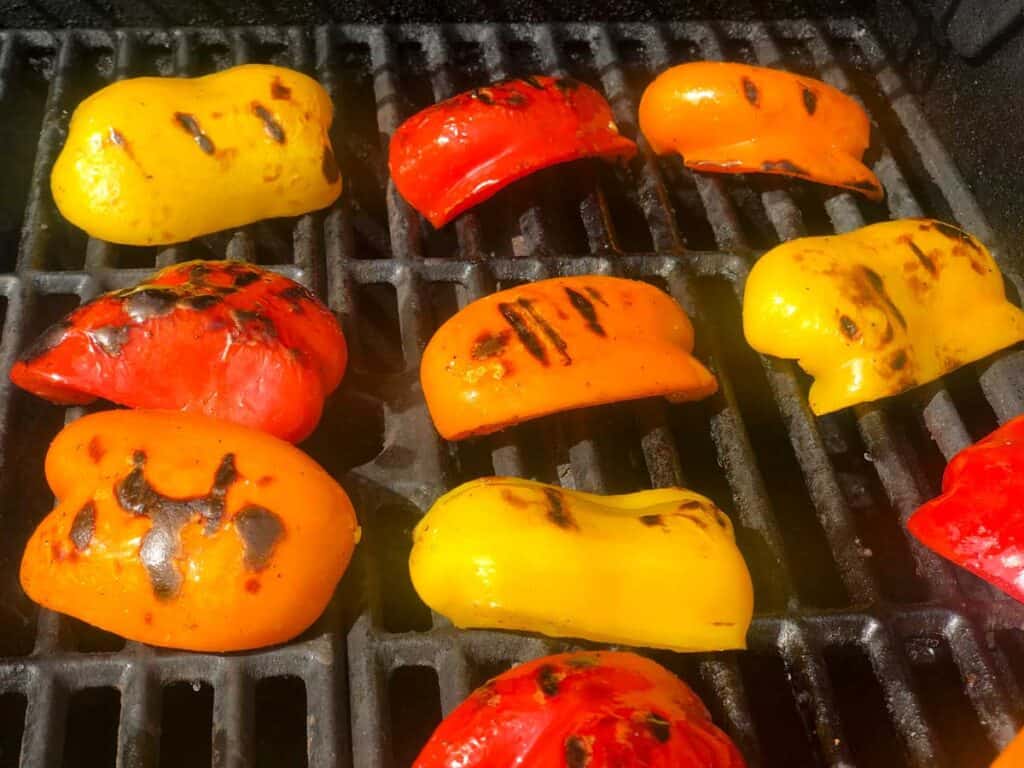 red, orange, and yellow bell peppers on grill