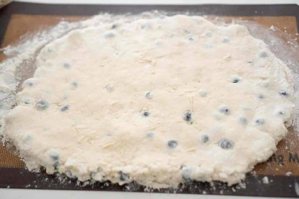 blueberry buttermilk biscuit dough rolled out on silicone mat