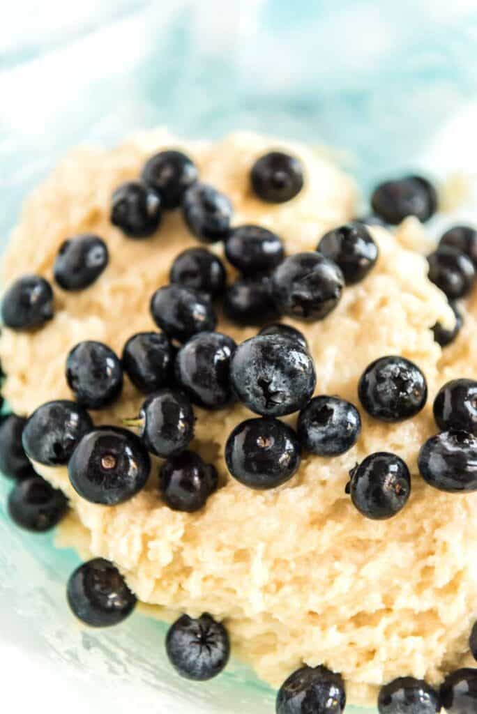 blueberries over muffin batter in glass bowl