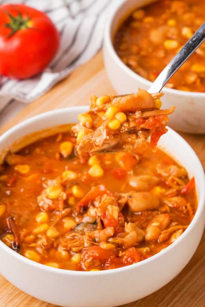 spoon holding Brunswick stew over two bowls of the stew