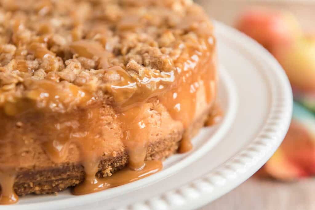 apple crisp cheesecake on white cake stand