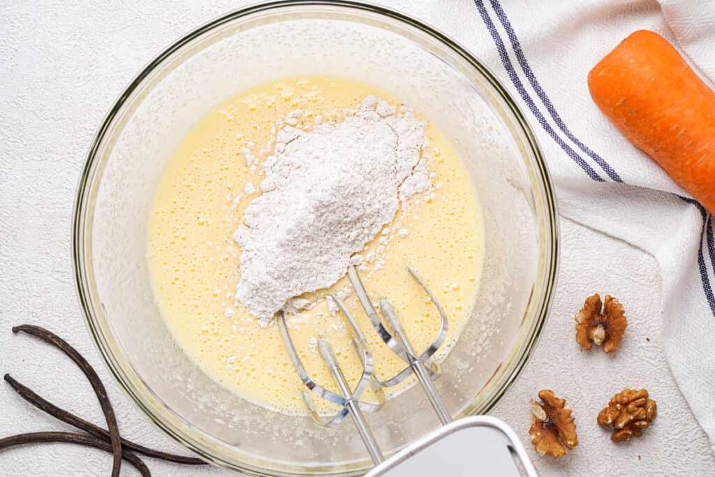 glass bowl with hand mixer mixing batter