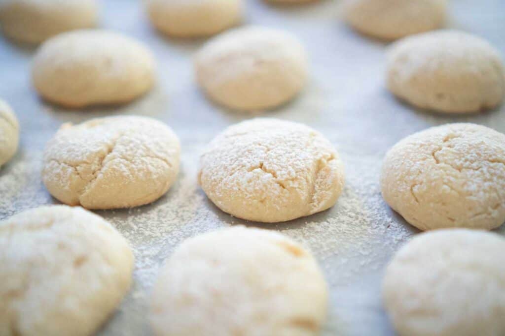 cream cheese cookies with powdered sugar dusting on parchment paper