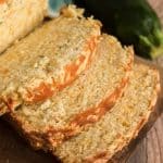 close up of sliced cheddar zucchini bread with whole zucchini next to it