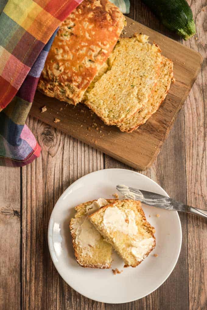 cheese zucchini bread on cutting board and white plate with butter