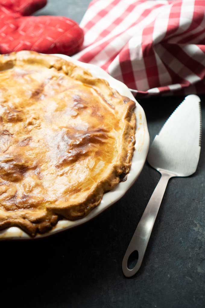 homemade chicken pot pie in ceramic pie dish with pie serving utensil next to it