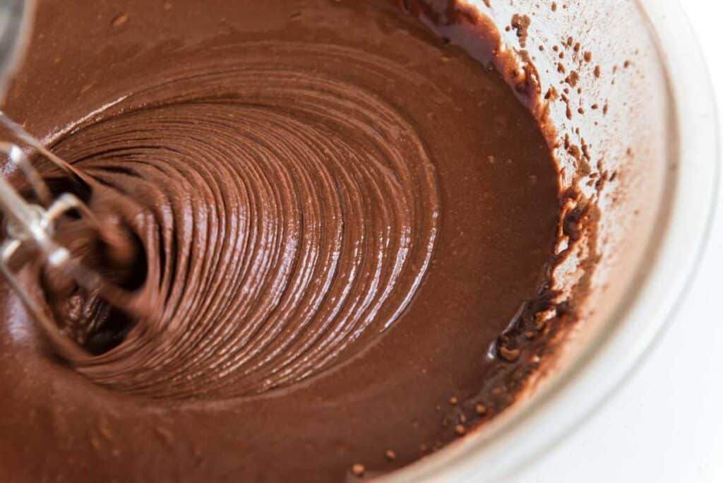 cake batter in glass bowl being mixed with mixer