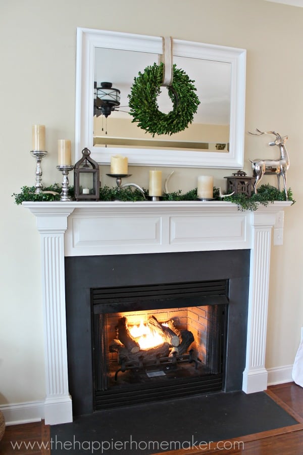 A fireplace decorated for fall with candles, antlers and silver accents