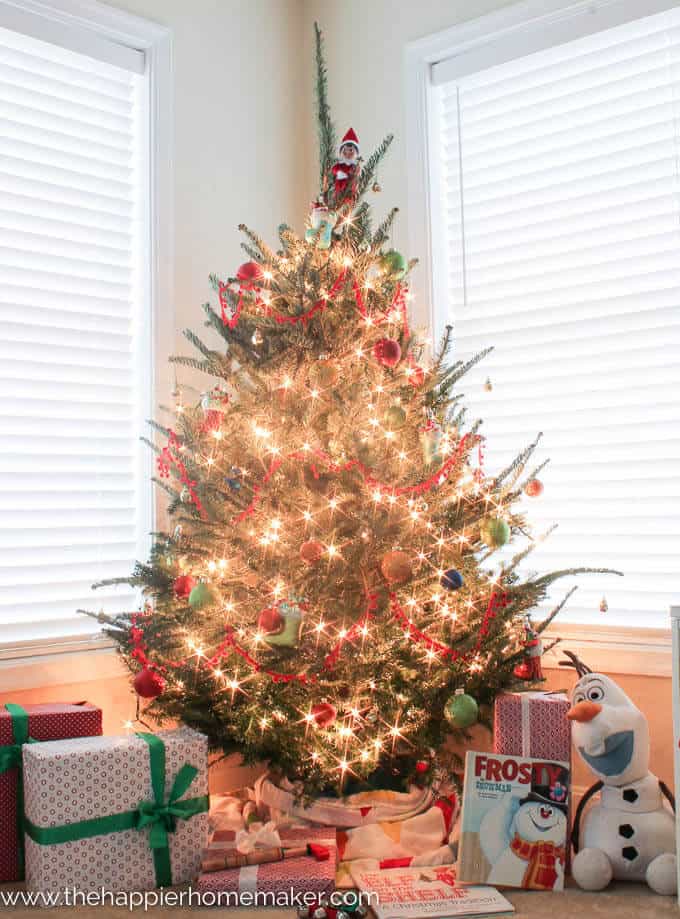 A lit up Christmas tree sitting in front of two windows