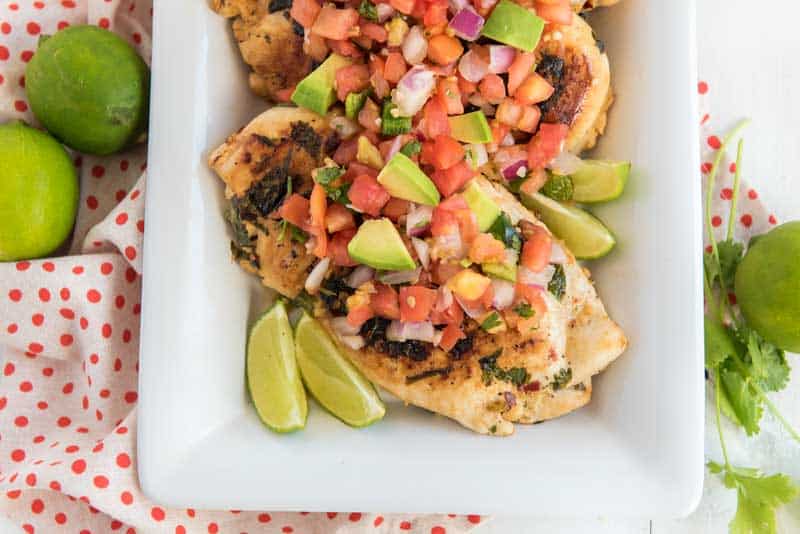 An over head picture of cilantro lime chicken on a white dish garnished with lime wedges