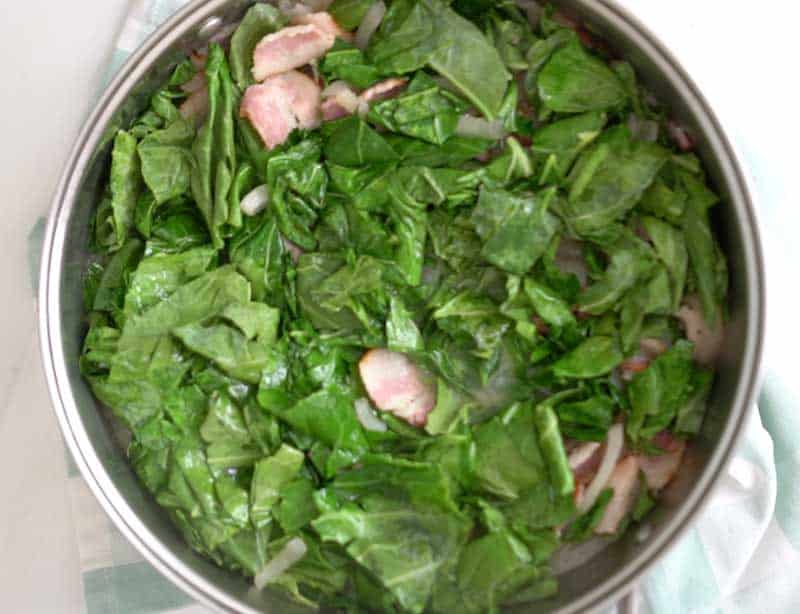 large skillet with sliced collard greens and chopped bacon