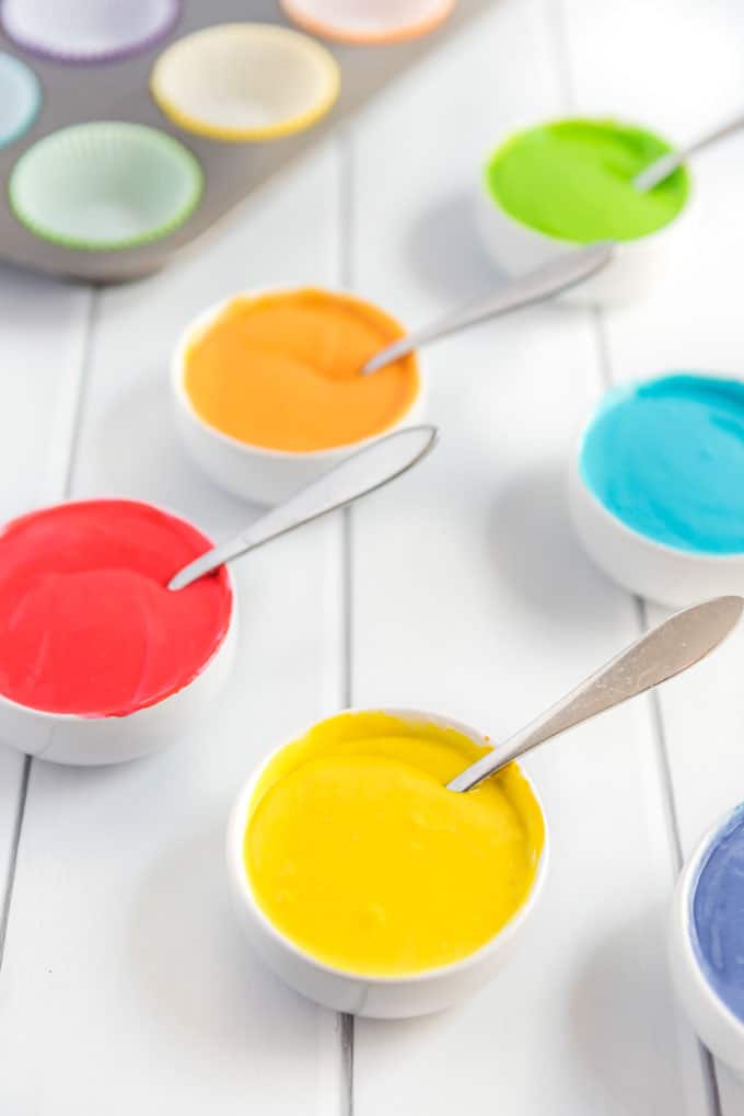 colored cupcake batter in bowls with spoons