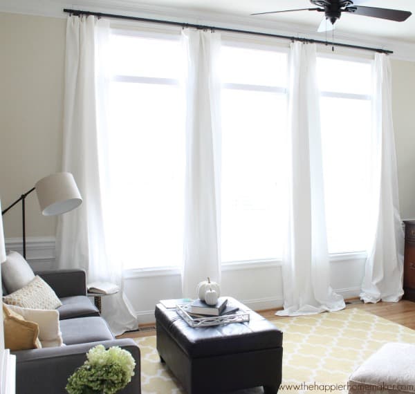 large living room window with white curtains and yellow rug
