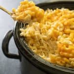 scooping crock pot mac and cheese out of slow cooker