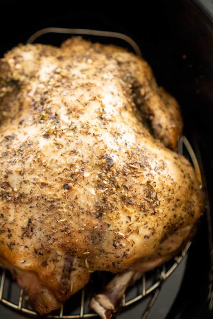 whole chicken seasoned with herbs in black slow cooker