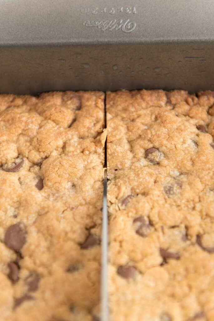 knife cutting cookie bars in pan