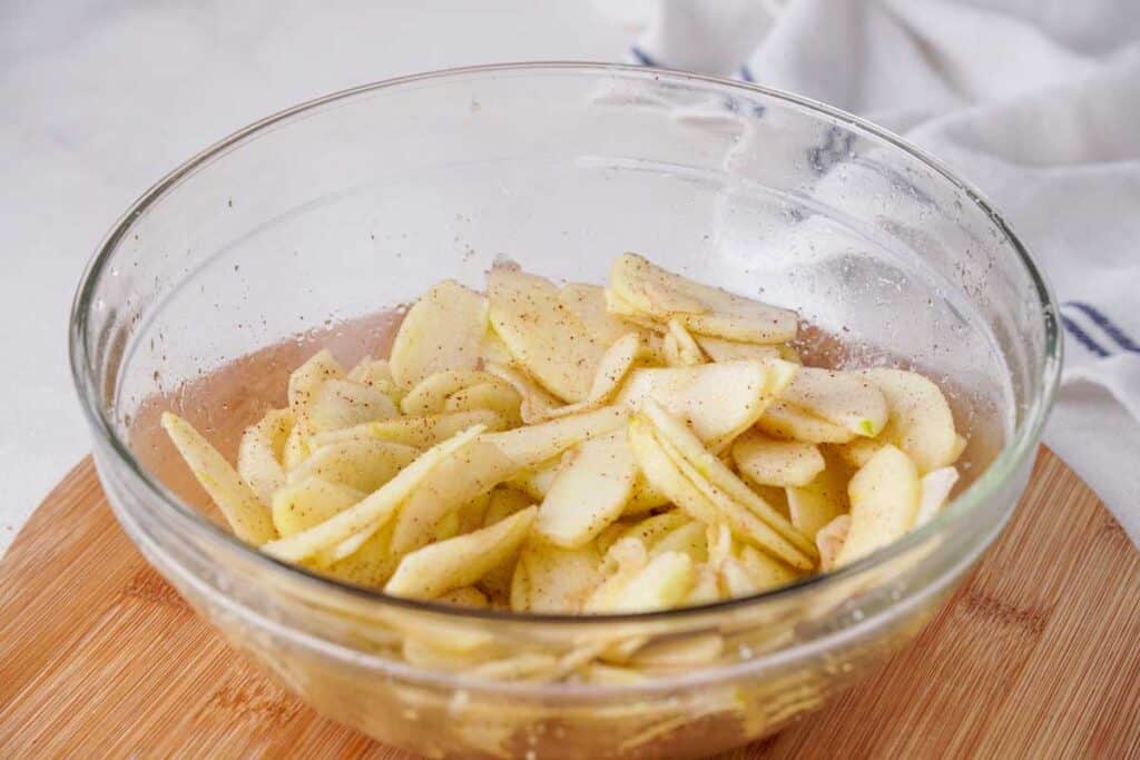 sliced apples with spices in glass bowl