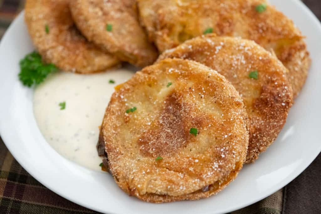 slices of fried green tomatoes on white plate with ranch