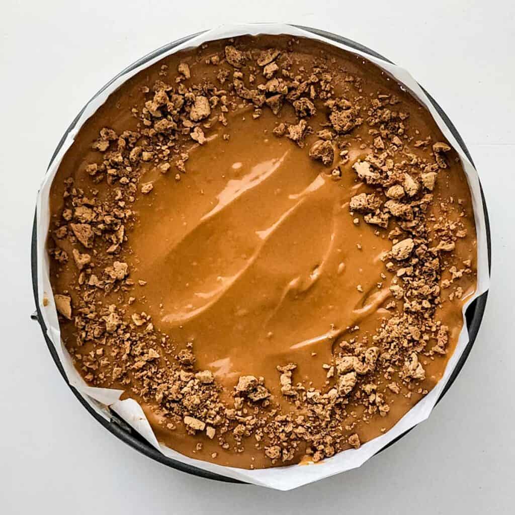 cheesecake topped with caramel sauce and crushed gingersnaps