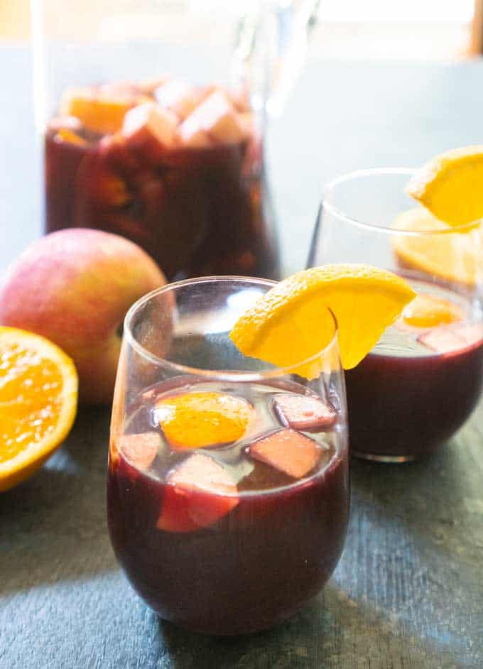 red wine spanish sangria in stemless glass with chopped fruit apples oranges