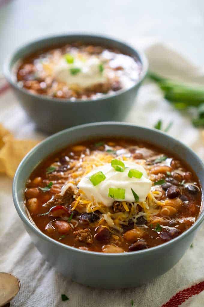 close up of Taco Soup in 2 gray ceramic bowls topped with sour cream and green onion