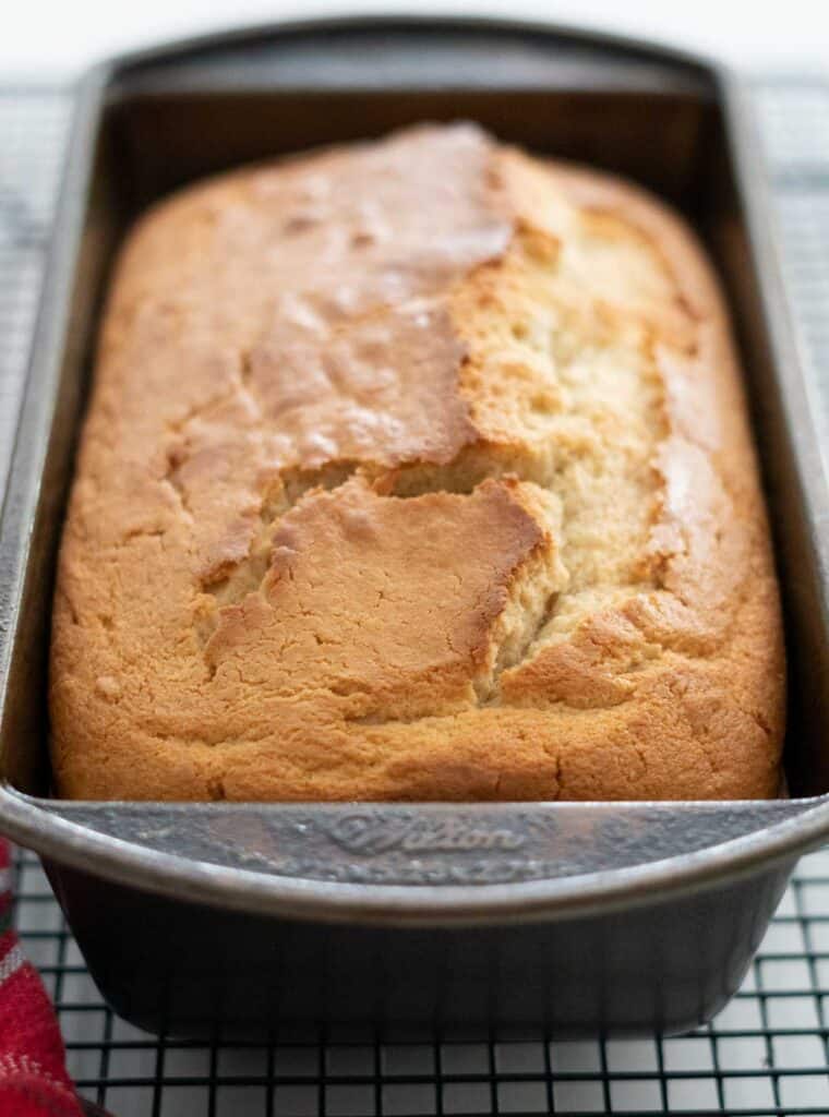 loaf of eggnog bread in pan on cooling rack