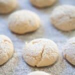 cream cheese cookies with powdered sugar dusting on parchment paper