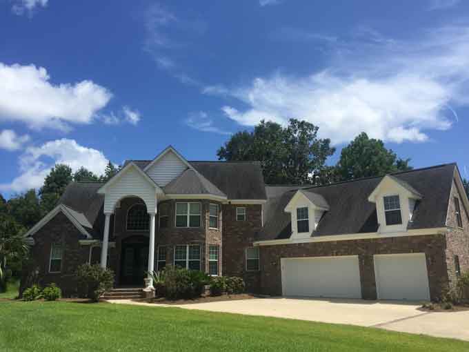 large brick home with two story arched entryway and three car garage