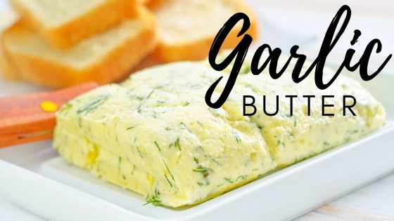 garlic butter on white plate with bread in the background