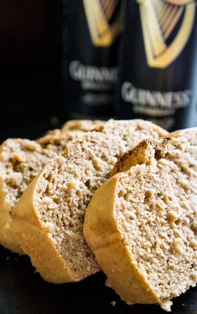A close up of three slides of Guinness beer bread with two cans of Guinness in the background