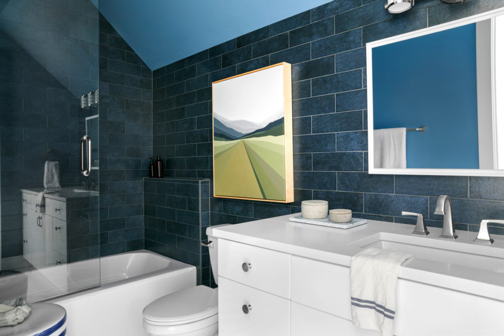 hgtv dream home bathroom with navy blue subway tile, painting, and mirror on wall and white vanity