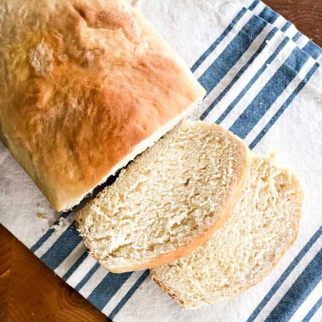 loaf of homemade white bread with two slices cut