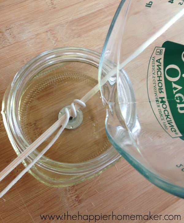 glass measuring cup pouring melted wax into mason jar