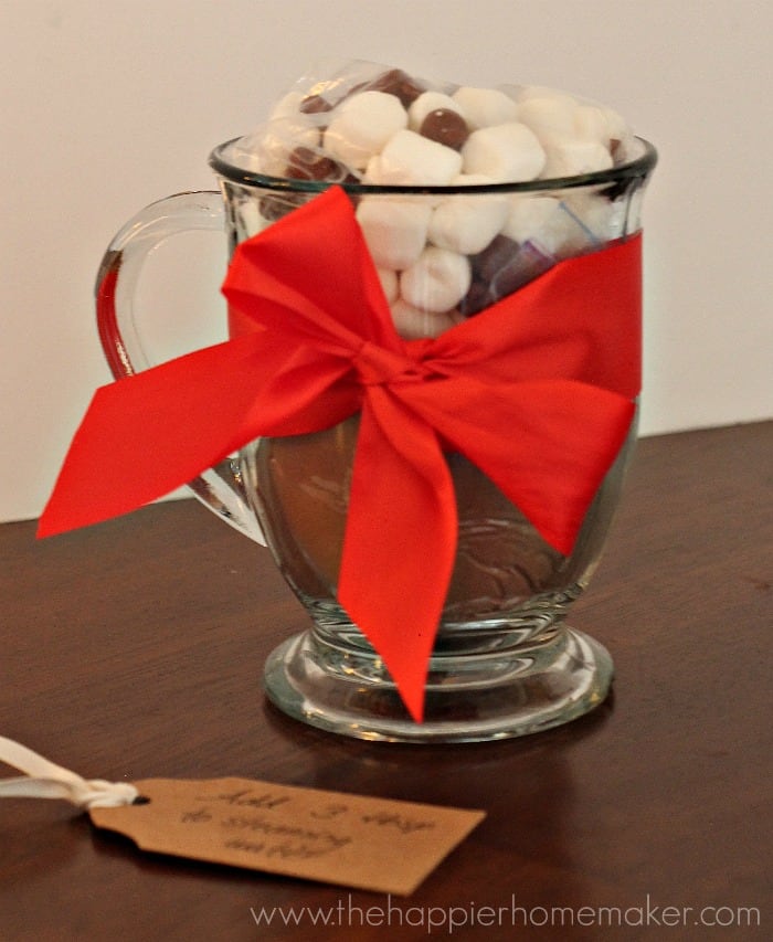 A glass jar full of hot coco mix and mini marshmallows tied with a red ribbon