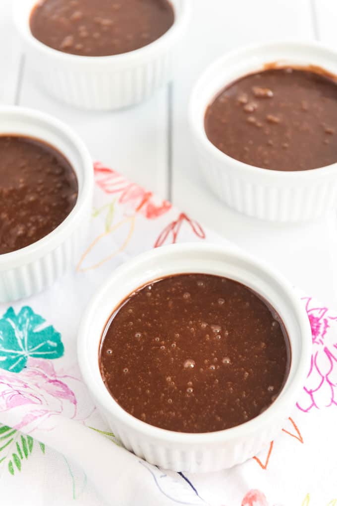 white ramekins filled with chocolate melting cake batter on colorful patterned napkin