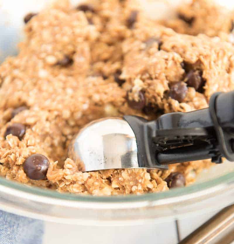 scooping peanut butter oatmeal cookie dough out of mixing bowl with cookie scoop