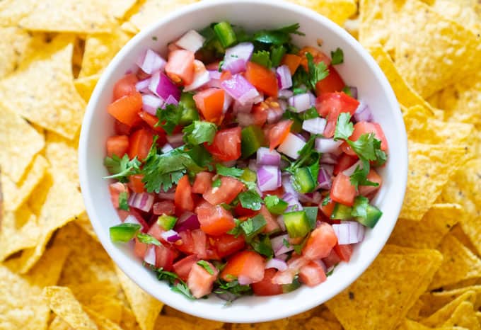 pico de gallo in white bowl surrounded by tortilla chips