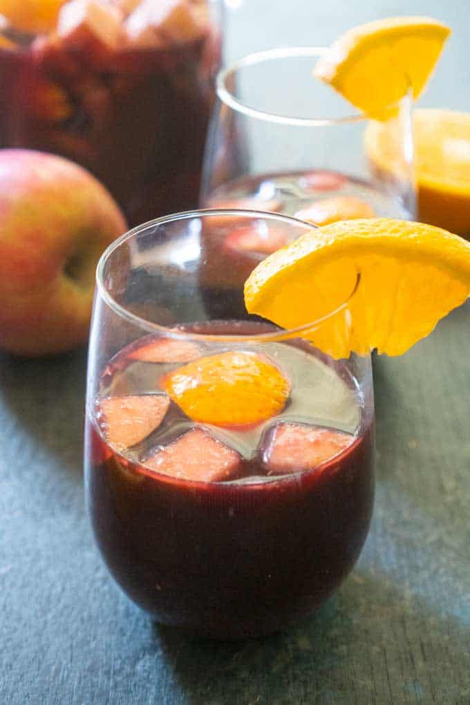 red wine sangria with cut apples and oranges in stemless wine glass