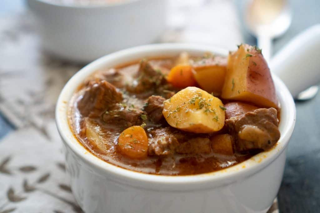 A close up of a white bowl with beef stew