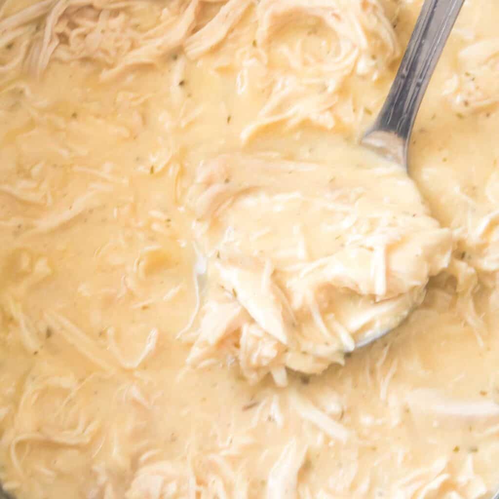 instant pot chicken and gravy being scooped with a large spoon