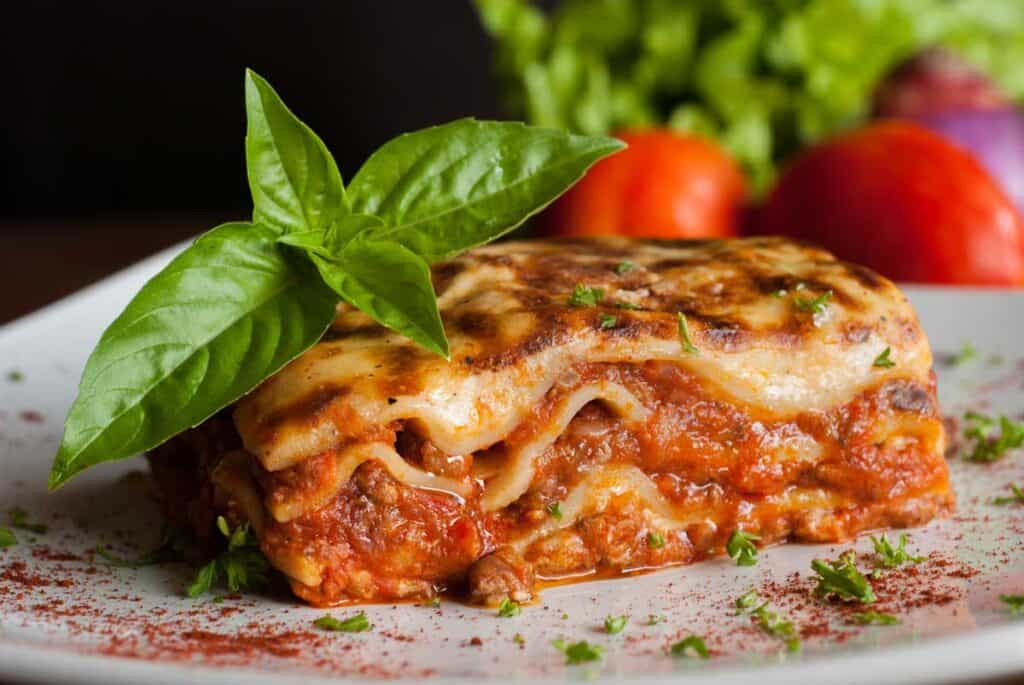 slice of lasagna on plate garnished with basil sprig