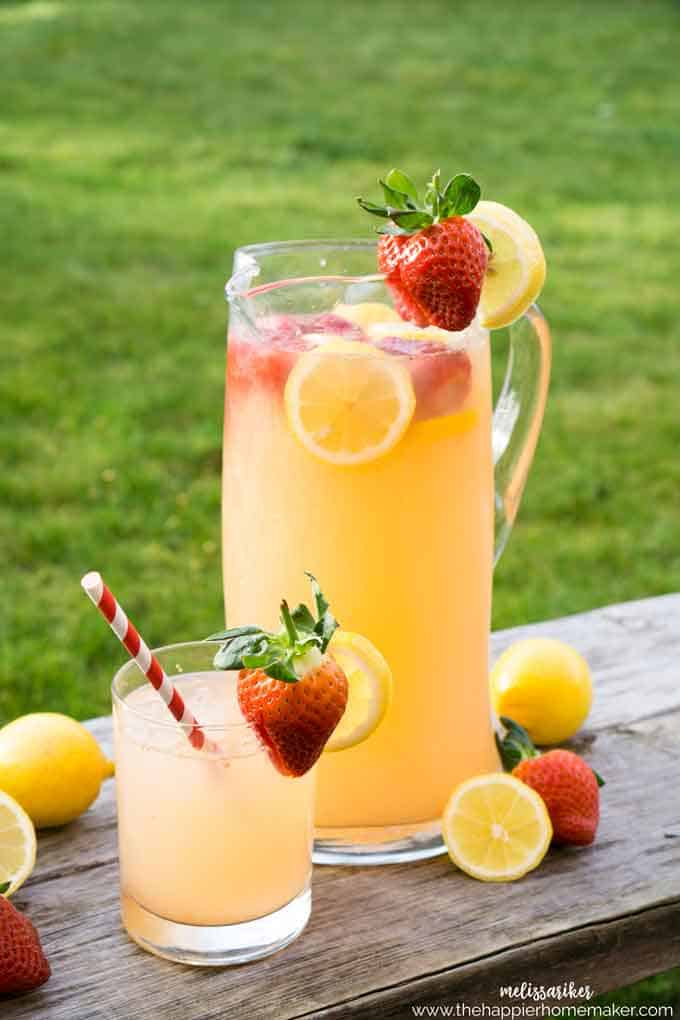 pitcher of strawberry lemonade with fresh lemons and strawberries
