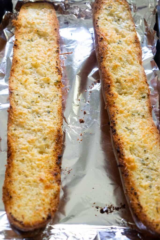 french bread cut in half to make garlic bread on baking sheet lined with foil