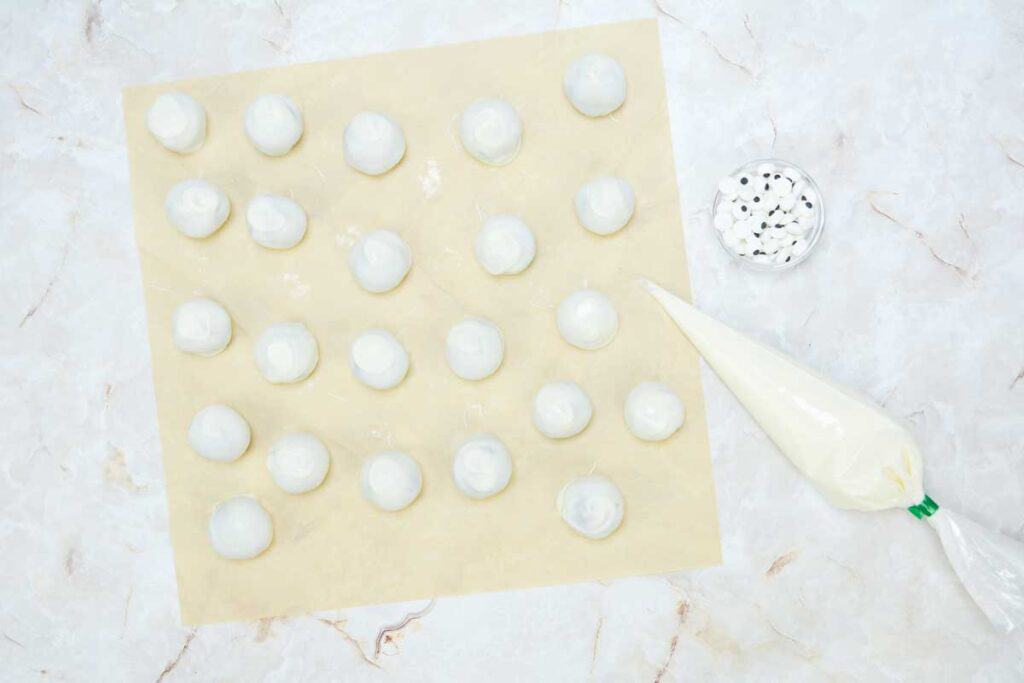 white truffles with piping bag and eyeball sprinkles