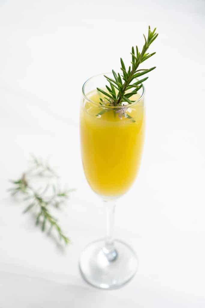 mimosa in champagne flute with sprig of rosemary