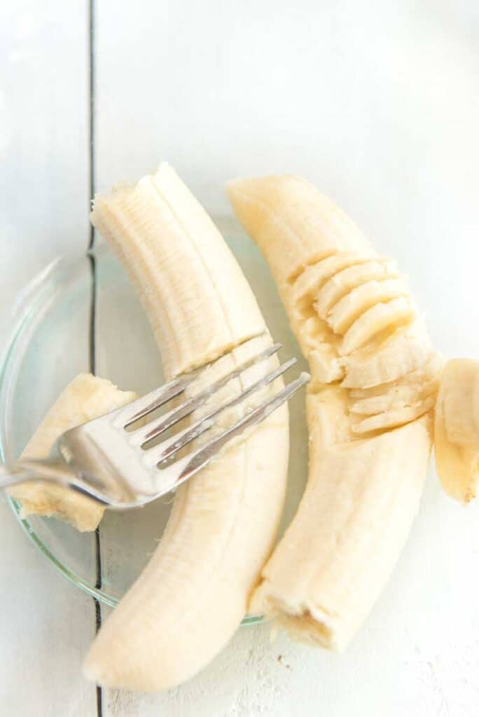 mashing bananas in glass bowl with fork