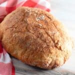 loaf of Dutch oven bread on red and white checkered towel